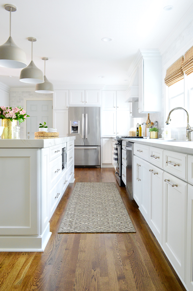 White kitchen with island and quartz countertops and gray light fixtures