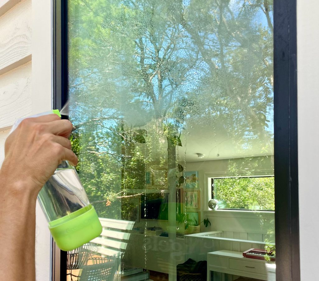 Spraying Exterior Window With Homemade Glass Cleaner