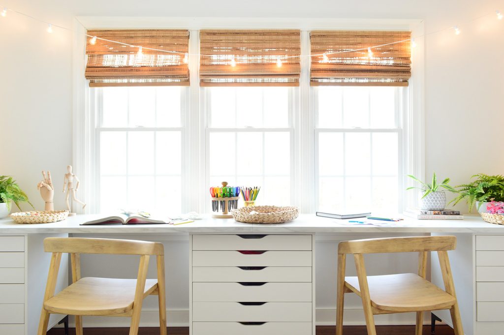 Straight View Of Kids Oversized Art Desk With Faux Marble Desktop In Front Of Window With String Lights