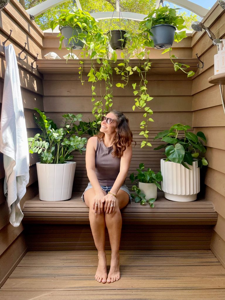 Sherry Sitting In Outdoor Shower With Plants and Behr Solid Stain Walls Tugboat