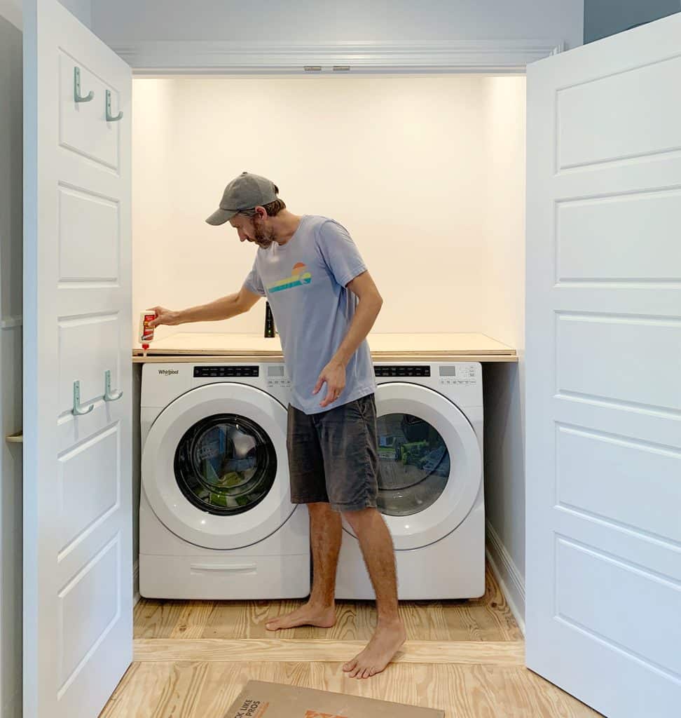 Man adding wood glue to front of laundry closet plywood counter