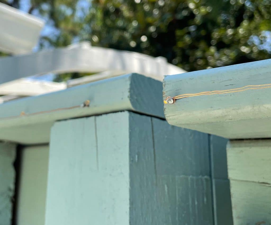 Detail Of Solar Fairy Light Wire Wrapped Around Nail In Fence