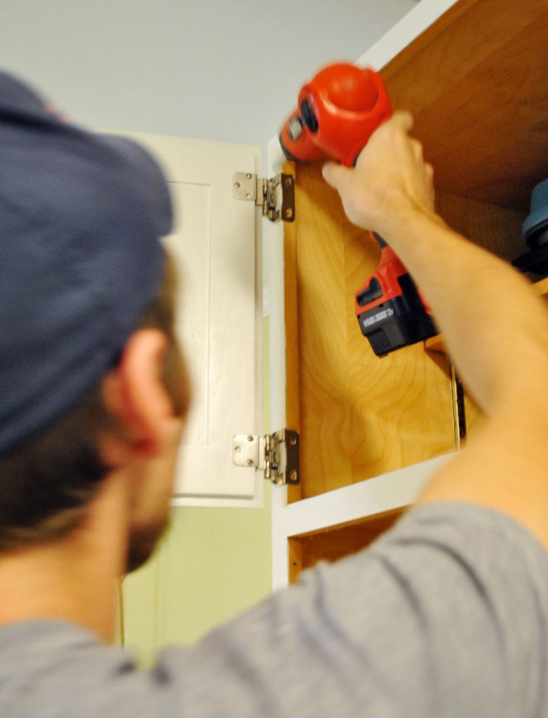 John reattaching cabinet door in painted kitchen